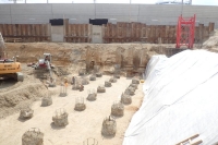 View into the building pit with uncovered  foundation piles; In the background the  retaining wall towards the railway station